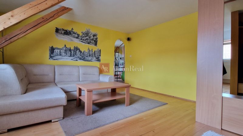 Living room with a sofa, wooden decor flooring, and yellow walls in a two-room apartment.