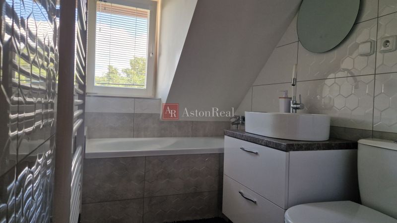 A bathroom in a 2-room apartment with a bathtub, a sink, and hexagonal tiles.