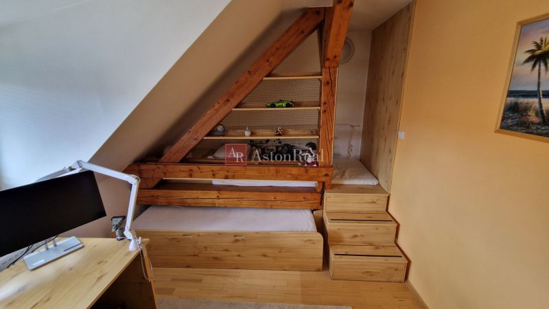 Attic room with wooden elements, a bed, and a desk in a 2-room apartment.