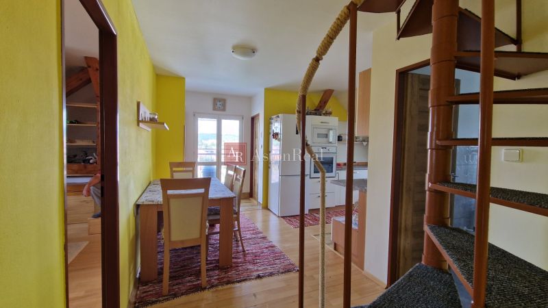 Bright kitchen with a dining table in a 2-room apartment with wood-patterned flooring.