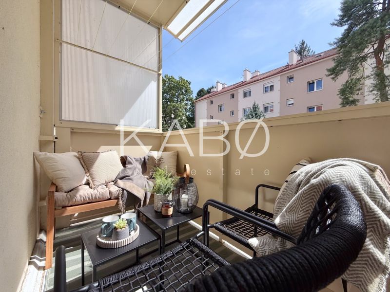 Balcony of a 2-room apartment with cozy seating and greenery.