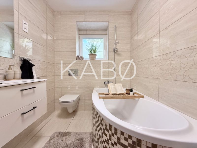 Elegant bathroom in a 2-room apartment with a bathtub, sink, and toilet.