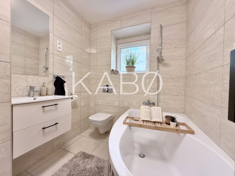 Bathroom with a bathtub and a sink in a 2-room apartment, beige tiles.