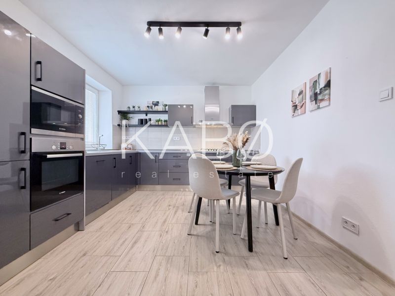 Modern kitchen in a two-room apartment with a wooden decor floor and a dining table.