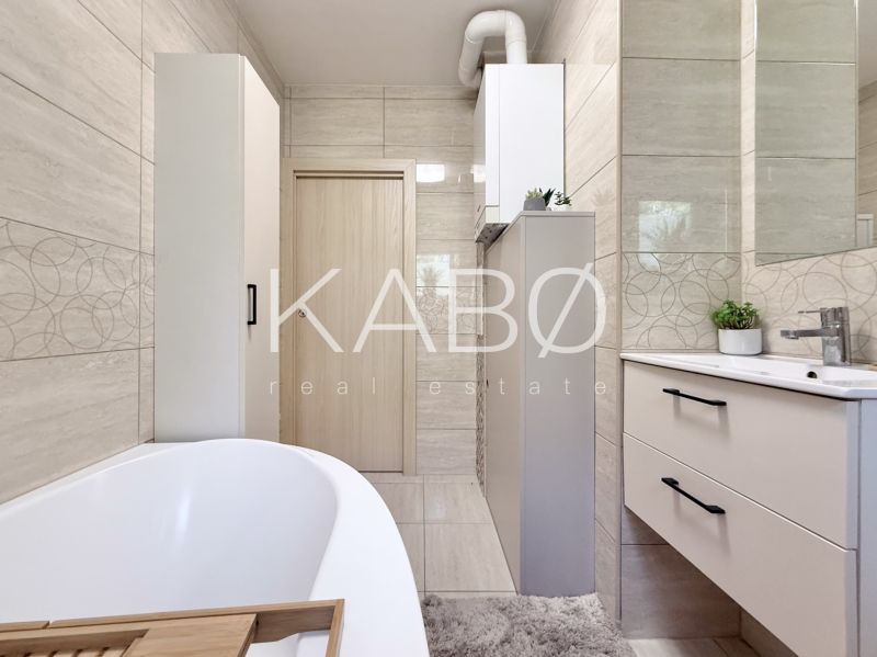 A bathroom in a 2-room apartment with a bathtub, furniture, and tiles decorated with geometric patterns.