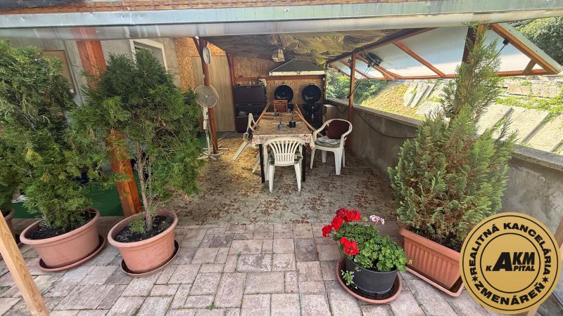 Terrace of a family house in Zvolen with wooden decor, a table, and potted plants.