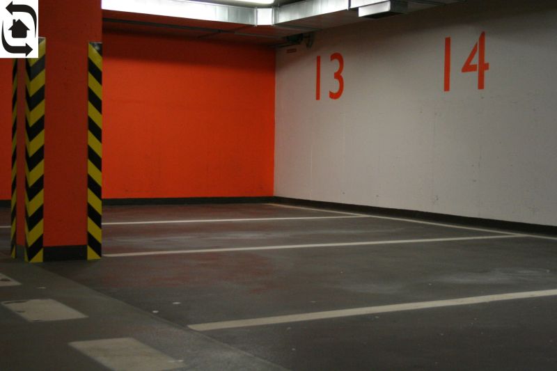 Parking spaces and an orange wall in the garage with yellow and black pillars.