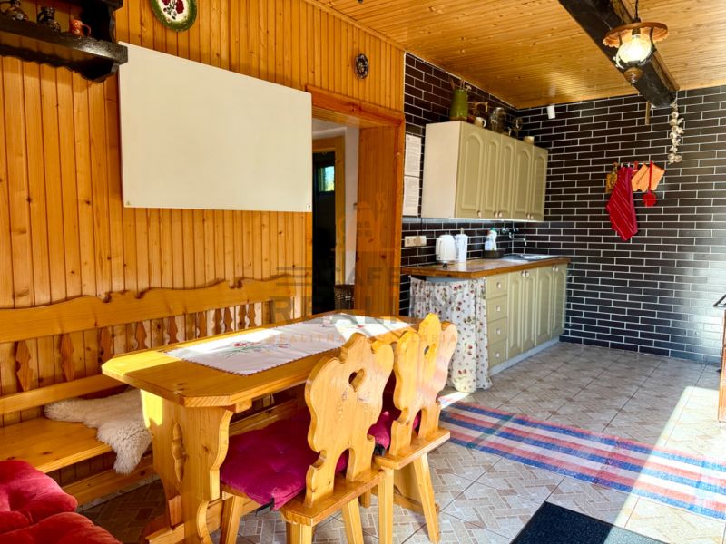 Wooden interior of a kitchen with a dining table and chairs in a family house.