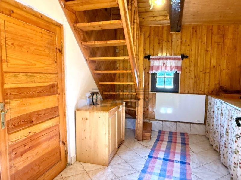 Interior of a family house with wooden staircase, ceiling, and doors, tiled floor.
