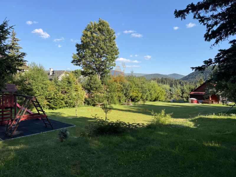 A family house in Šumiac on Jána Švermu Street, a grassy garden with a playground surrounded by nature.