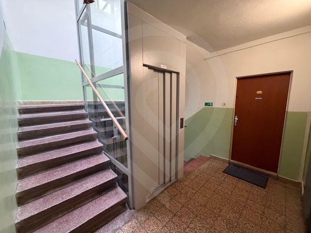 The apartment building has stairs, an elevator, and the door to a 3-room apartment.