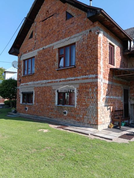 A family house in Ovčiarsko with an unplastered brick facade and a green lawn for the plots - living.