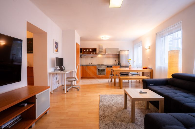Living room with kitchen in a 4-room apartment, with a wooden decor floor and versatile furnishings.