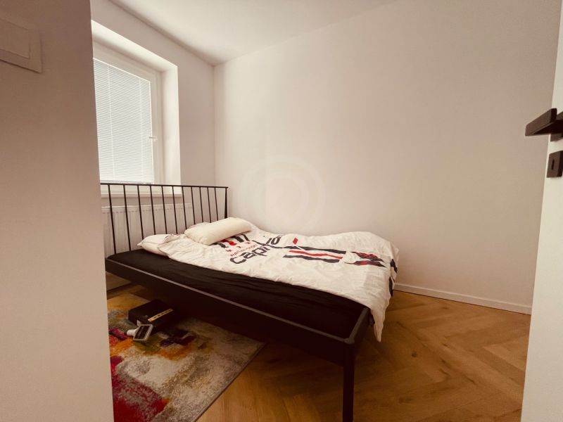 A bedroom with an iron bed and a wooden decor floor in a 4-room apartment.