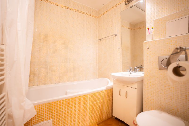 Bathroom in a 4-room apartment with a bathtub, sink, and toilet, light tiles.