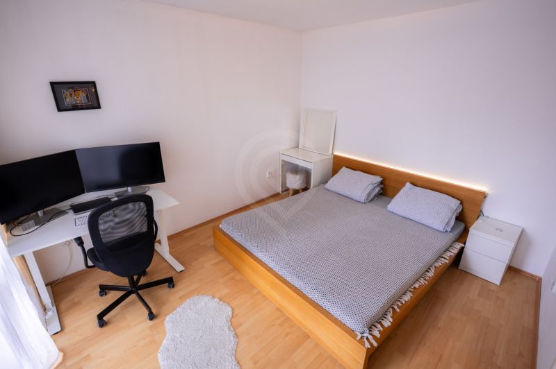 Bedroom with a bed, desk, and wooden decor flooring in a 4-room apartment.