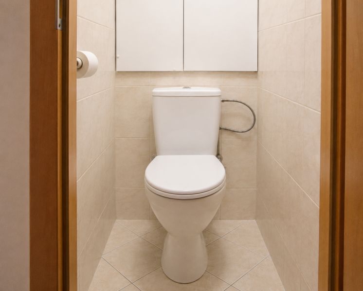 A bathroom in a 2-room apartment with beige tiles and a toilet.