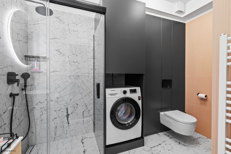 A bathroom with a washing machine and shower in a 3-room apartment decorated with marble tiles.
