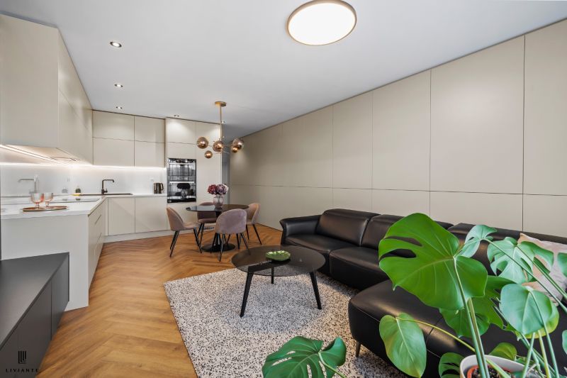 Interior of a 3-room apartment with an open kitchen, wooden decor flooring, and plants.