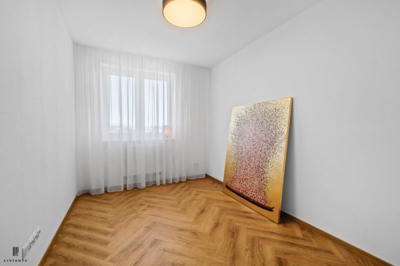 A bedroom in a 3-room apartment with a painting, white curtains, and a floor with a wooden design.