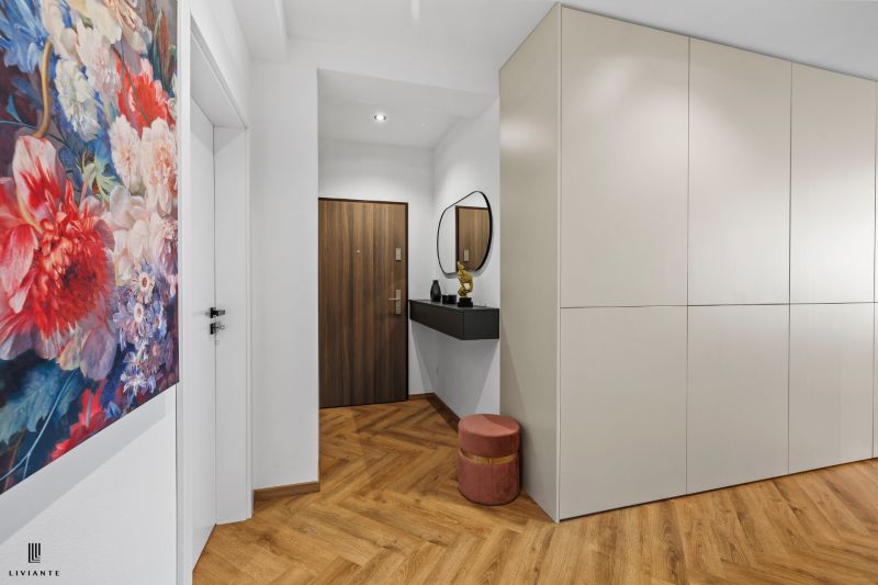 Entrance hall in a 3-room apartment with wood-patterned flooring and a colorful painting.