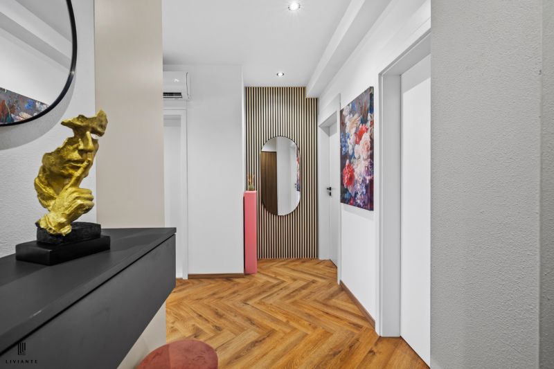 A hallway in a 3-room apartment with decoration, a floral painting, and a floor with a wooden decor.