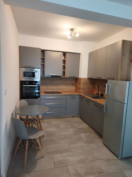 A kitchen in a studio apartment with a dining nook and gray cabinets.