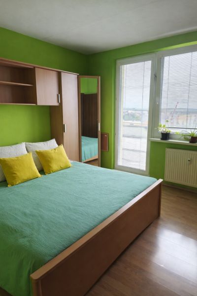 Green bedroom with a bed and a wardrobe in a wooden decor in a 3-room apartment.