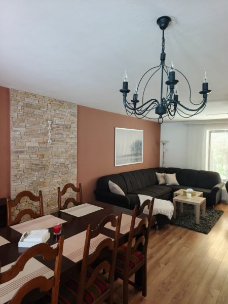 Living room in a family house with a sofa, dining table, and wooden decor flooring.
