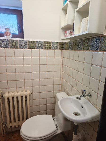 Bathroom in a family house with a toilet, sink, and window, tiled.