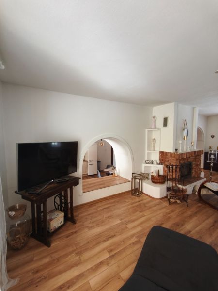 Living room with a fireplace in a family house, floor with wooden decor, TV on a stand.