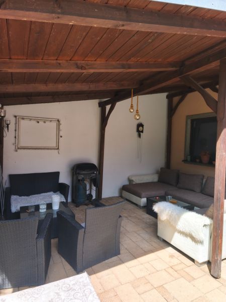 Covered terrace of a family house in Mankovce with rattan furniture and a fireplace.