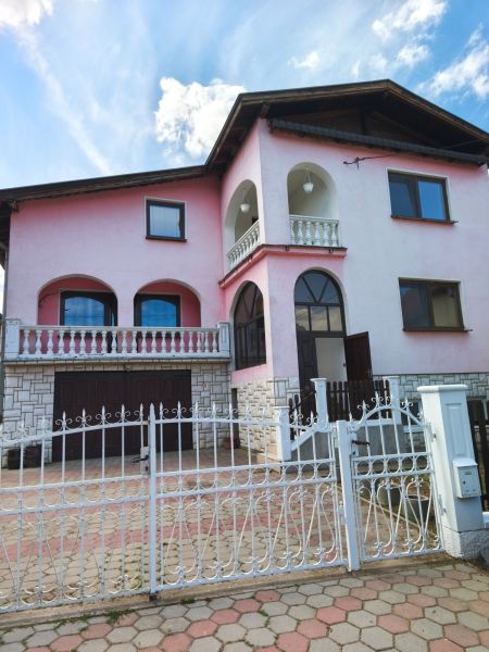 A family house in Mankovce with a pink facade, a floor, and a wrought iron fence.