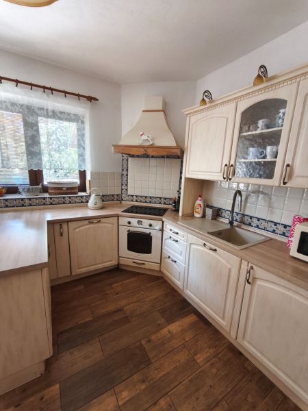 A kitchen with wood-patterned flooring, white cabinets, and tiles in a family house.