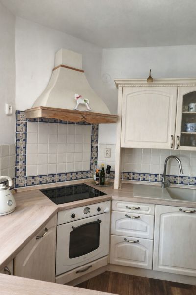 White kitchen with a cooktop, extractor hood, and wooden decor flooring in a family house.