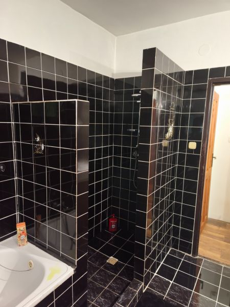 A bathroom in a family house with black tiles and a shower corner.
