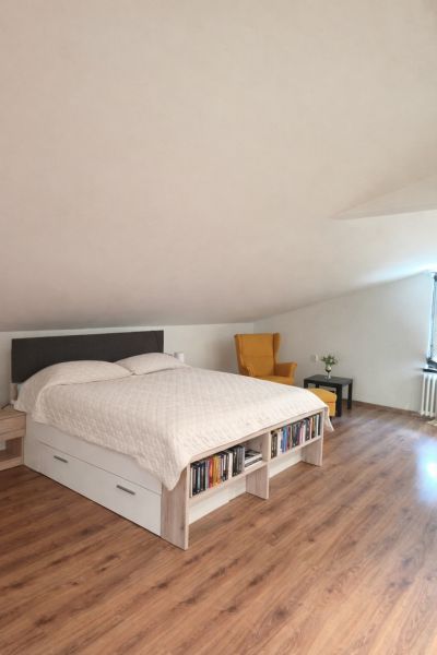 Bedroom in a family house with a wood-patterned floor, a bed, and a chair.