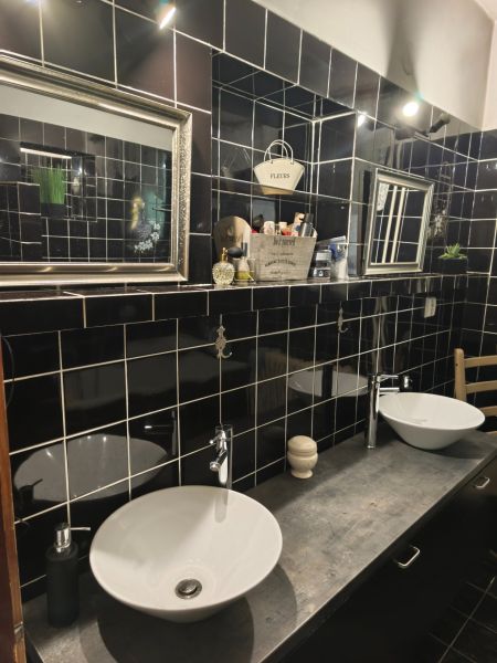 A bathroom in a family house with black tiles, two sinks, and mirrors.