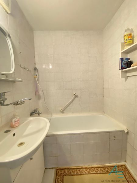 A bathroom with a bathtub, sink, and white tiles in a 4-room apartment.