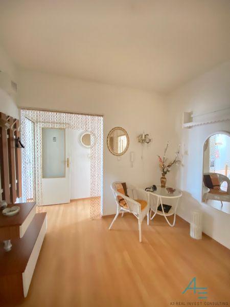 Interior of a 4-room apartment with a wooden decor floor, decorative mirrors, and wicker chairs.