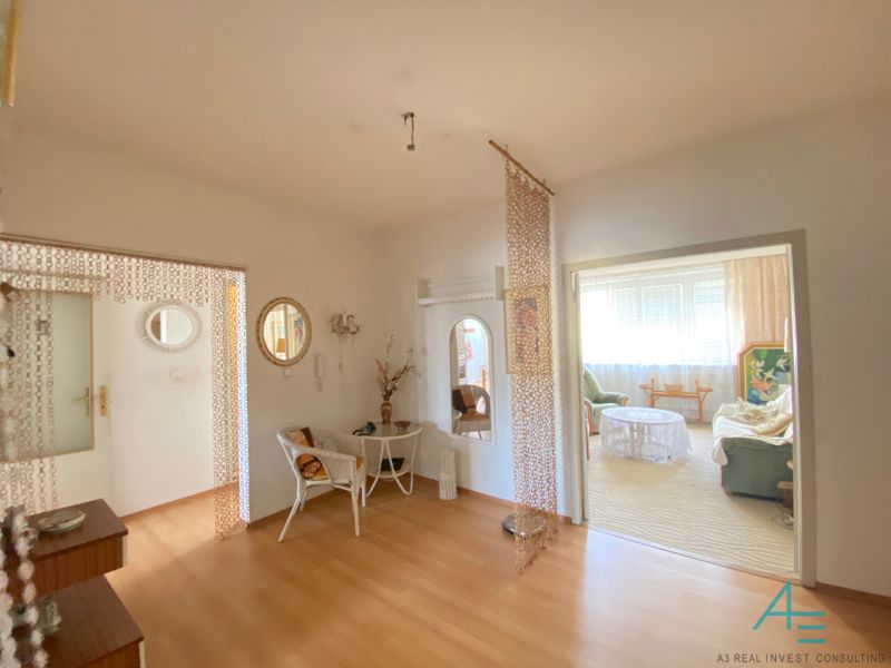 Interior of a 4-room apartment with a wooden decor floor, chair, and mirrors.