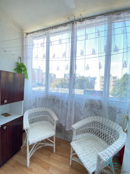 Loggia with wicker chairs and a view from a 4-room apartment with a wooden decor floor.