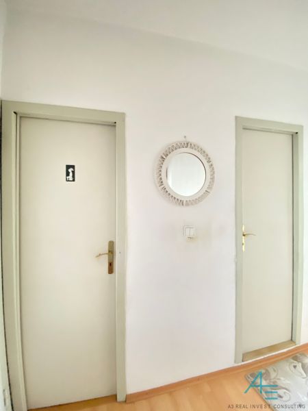 A hallway in a 4-room apartment with a wooden decor floor and two doors.