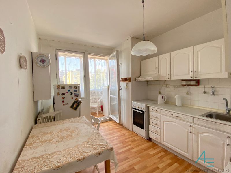 A kitchen in a 4-room apartment with a glass-enclosed balcony and a wooden decor floor.