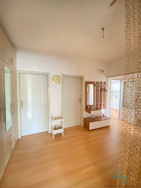 Entrance hall of a 4-room apartment with a wooden decor floor and a mirror.