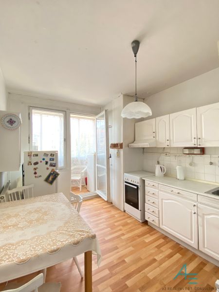 A kitchen in a 4-room apartment with white cabinets and a wooden decor floor.