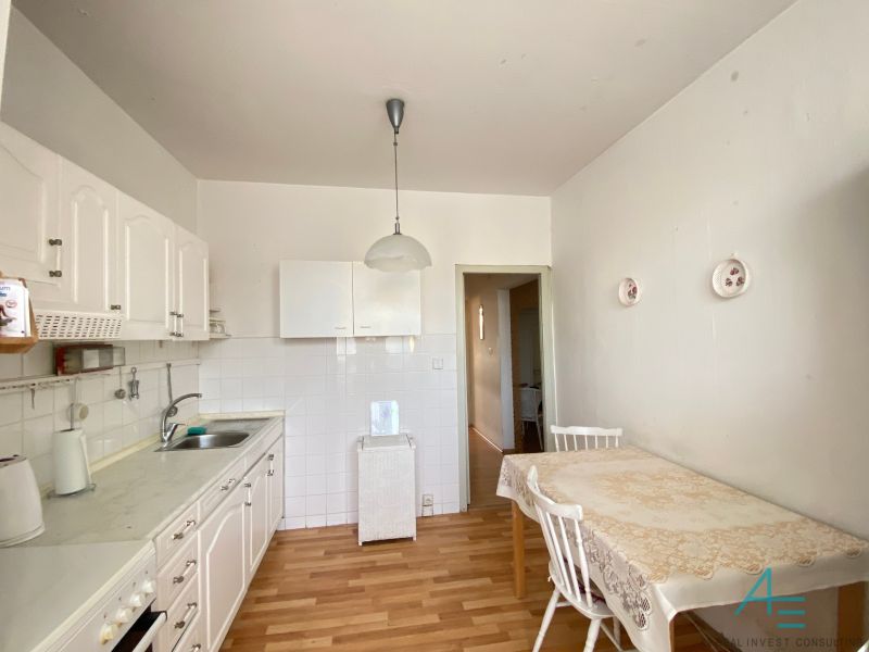 A kitchen in a 4-room apartment with white cabinets and a wood-patterned floor.