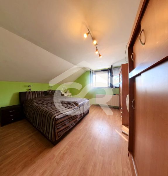 Attic room with a bed, wardrobe, and wooden decor flooring in a family house.
