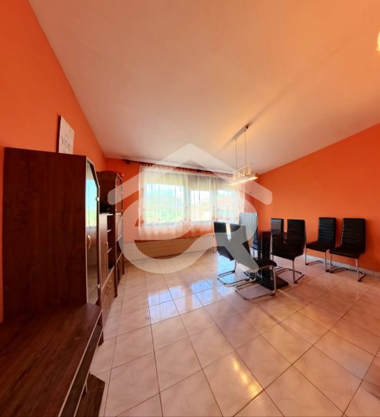 Living room in a family house with orange walls and black chairs.