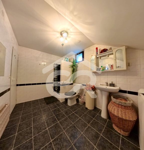 Bathroom with tiles, sink, mirror, and toilet in a family house.